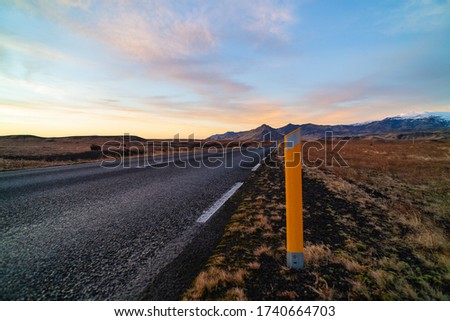 Road number one with a kilometer pole in the foreground in Iceland with snow-capped mountains in the background. Circular road around Iceland. Safety of movement. Roadside
