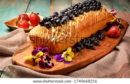 Cake with white chocolate on black table with blueberry and strawberry, home made cake