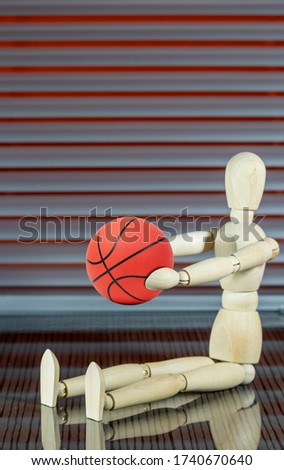 Wooden dummy with basketball in front of a jalousie plays with the ball