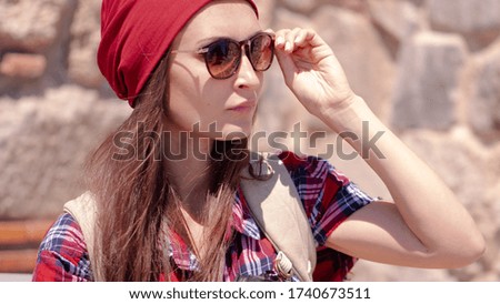 Young female traveler with backpack and red hat. Woman tourist takes a picture on camera. Hipster Girl traveler with backpack. Springtime or Summer in Europe. Travel and Vacation