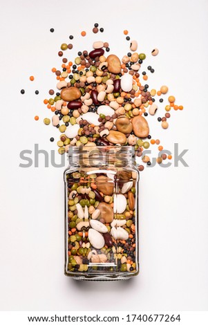glass jar with a large variety of dried legumes in the foreground, top view, isolated from the white background Royalty-Free Stock Photo #1740677264