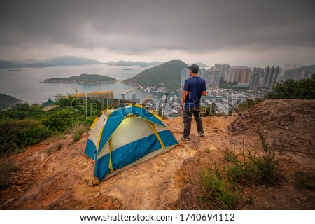 Man traveler Taking photo on top of mountains near of tent camping gear, Male hiking at brick hill (nam long shan)That overlooks the Aberdeen Bay, People living healthy active lifestyle outdoors 