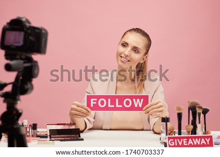 Young woman smiling at camera and says to her followers to follow her beauty blog
