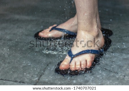 Flip flops on the feet of a person washing in the shower. Close up. Royalty-Free Stock Photo #1740707021