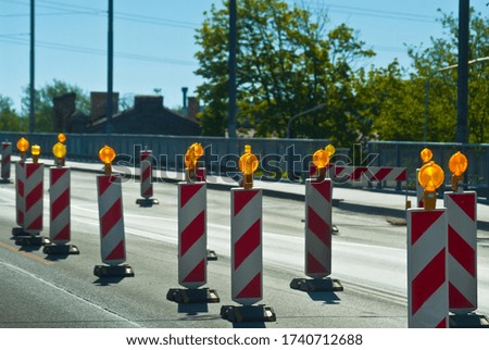 fence posts on the road with yellow warning lights