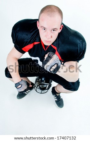 American football player sitting on his helmet, isolated on white background