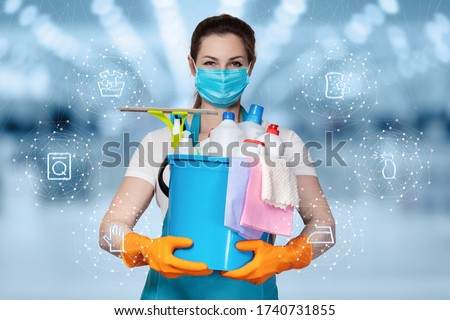 The concepts of cleaning and disinfection services.A cleaning lady in a mask stands on a blurry background with cleaning products. Royalty-Free Stock Photo #1740731855