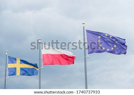 Flags fluttering in the wind: Swedish, Polish, European Union. Three flags against a bright blue sky on a sunny day