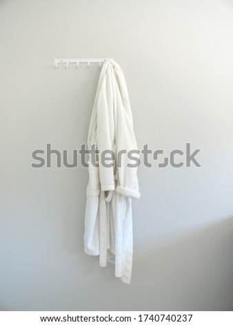 White robe hanging on a gray wall behind the door                                Royalty-Free Stock Photo #1740740237