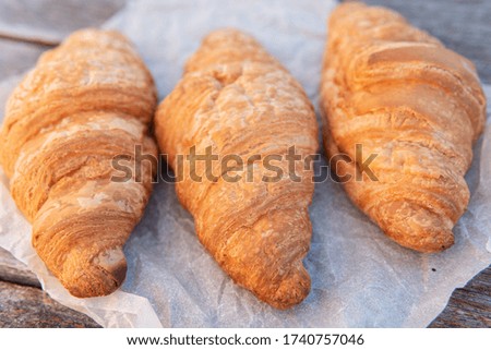 Three croissants on parchment. lie parallel to each other. perpendicular to the camera