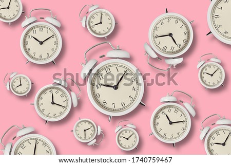 White vintage alarm clocks with shadows on pink background, top view minimal styly