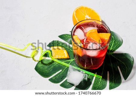 Summer homemade Cold red sangria cocktail with Orange and ice in glass on gray concrete stone background