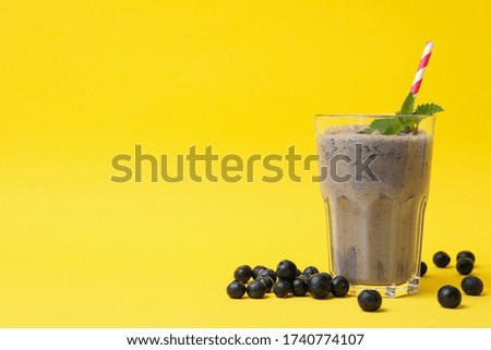 Glass of delicious berry milkshake on yellow background. Summer drink