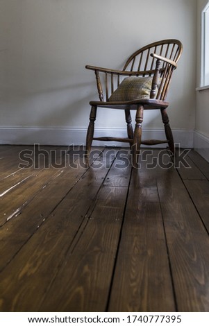 wooden chair with a cushion in a corner of an old english house with wooden floor