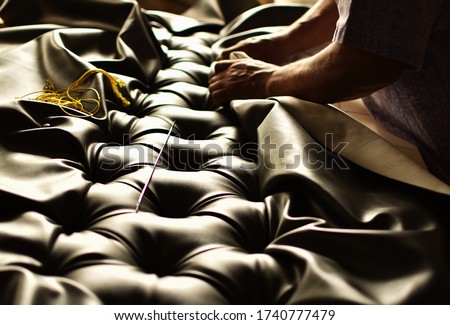 creative hands working on the upholstery of a capitoned headboard Royalty-Free Stock Photo #1740777479
