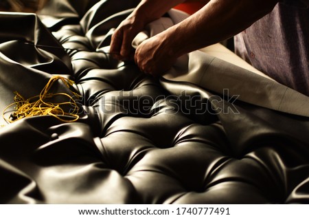 creative hands working on the upholstery of a capitoned headboard Royalty-Free Stock Photo #1740777491