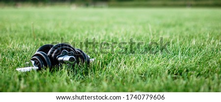 Dumbbells on the grass. Pattern, background, texture. Two Dumbbells over Green Grass at sunny day with neighborhood at background. Ideal fit Street Workout or Outdoor fitness.Free space for your text.