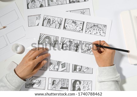 The animator artist draws in pencil a storyboard for the cartoon. Pre-production for the video film. The designer creates sketches for the comics.  Royalty-Free Stock Photo #1740788462