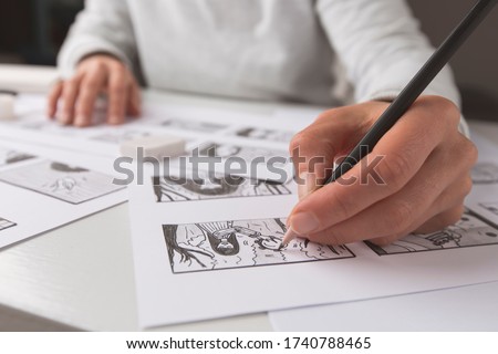 The animator artist draws in pencil a storyboard for the cartoon. Pre-production for the video film. The designer creates sketches for the comics.  Royalty-Free Stock Photo #1740788465