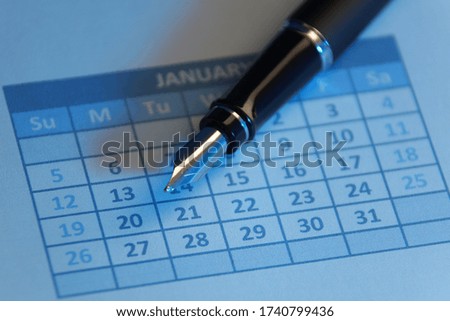 Fountain pen on calendar with blue light
