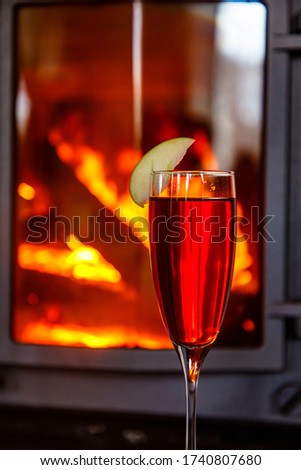 A glass of pink champagne against the background of a burning fireplace.