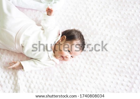 Infant beautiful baby lying down on white blanket. Picture with copy space