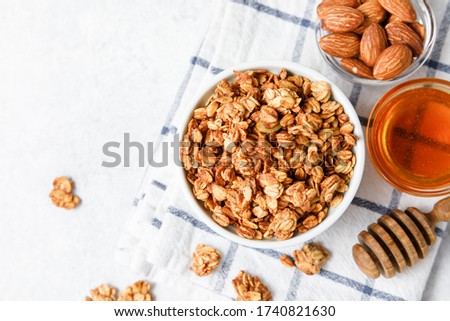 Homemade oatmeal granola bowl on white background. Healthy breakfast concept. Organic oat, almond and sunflower seeds baked with honey and olive oil until crispy crust. Top view, copy space