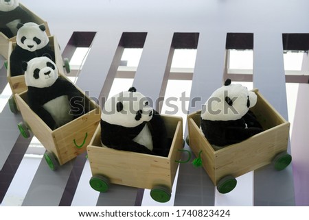 Toy pandas ride in a train car. Pandas in clapboards