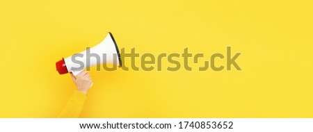 megaphone in hand on a yellow background, attention concept announcement, panoramic mock-up Royalty-Free Stock Photo #1740853652