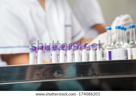 Barcodes on test tubes with technicians working in background