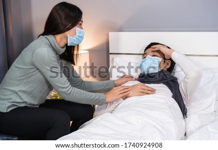 wife take care her sick husband on a bed at home, people must be wearing medical mask protecting from coronavirus(covid-19) pandemic
