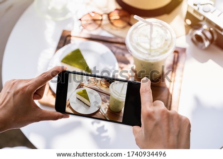 Young woman taking photo of food with smart phone in restaurant while traveling