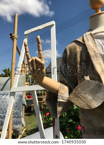 Wooden Mannequin wearing natural dyed kimono making I love you hand gesture. 