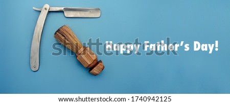 Straight edge razor and shaving brush with Happy Father’s Day text on blue horizontal background 