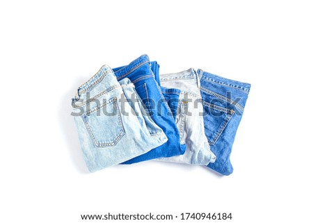 set of jeans trousers of different colors on a white background. flat lay, top view.