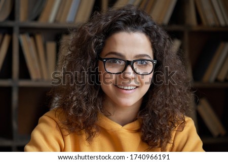 Smiling confident latin teen girl school pupil, college student or university teacher looking at camera. Happy hispanic woman wear glasses posing in library classroom. Close up headshot portrait. Royalty-Free Stock Photo #1740966191