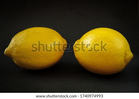 Lemons, two yellow lemons on a black background. Side view.
