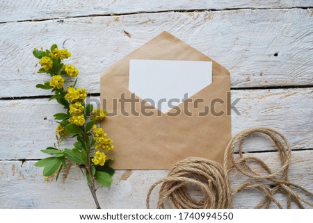 Artistic mockup for your artwork with beautiful flowers, kraft paper envelope and empty card  shot from the top. Flat lay minimalistic composition 
with space for text.