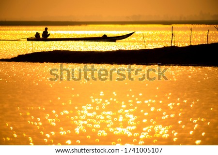 Beautiful nature with fishing boats running, golden light, reflection water, sunset of Lam Pao Dam in Kalasin Province, Thailand.