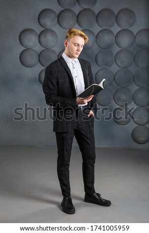 young businessman wearing black suit and white shirt reads his calendar