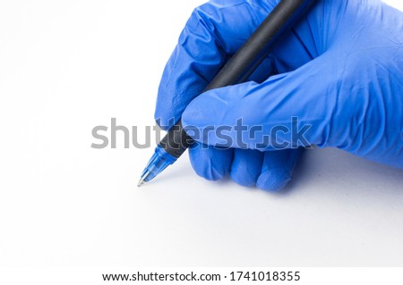 A female hand in a medical glove holds a pen and writes in the air on a white background. Copyspace. 