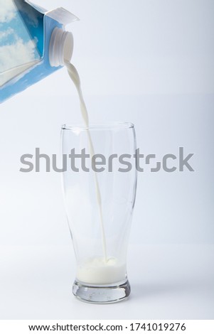 Pouring milk in a glass isolated against White background