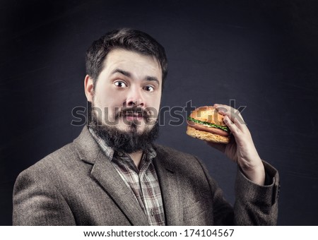 Man in jacket with beard holding hamburger at dark background