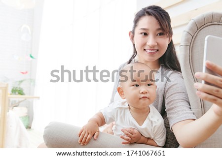 A young mother and baby with a cell phone camera