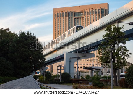 Japan. A train rides on a railway bridge against the background of an office building in Tokyo. Trip to the capital of Japan. Transport In Tokyo. Travel to East Asia. Japanese public transport.