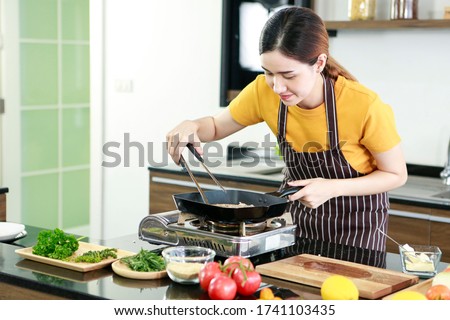 Asian women present fresh food. Shot housewife trying to cooking and showing steak in pan in kitchen in house to take picture for sell food box online. Work from home / Stay at home / covid19 concept 