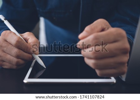 Business, digital technology, electronic signature, signing contract concept. Close up of business man with stylus pen signing on digital tablet, mobile app and working on laptop computer in office