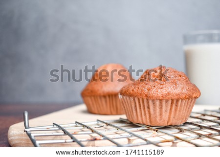 Banana cupcakes and a glass of milk on wooden table with copy space