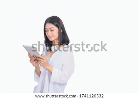 Pretty young smiley Asian business woman uses modern tablet.