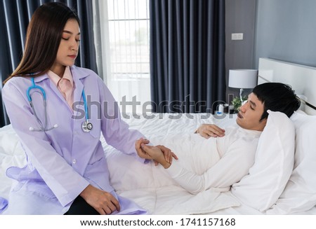 sick man lying in a bed while doctor checking his pulse